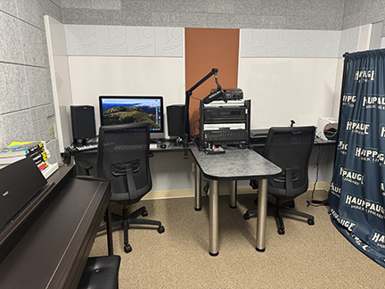 room with piano, desk, 2 chairs, and a/v equipment